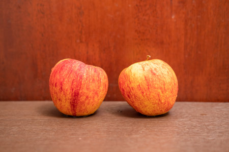 Orange-red apples on a wood grain backgroundの写真素材
