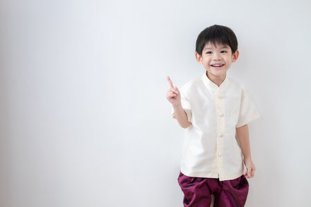 Asian boy Wearing traditional Thai clothing, standing with index finger upwards. on a white backgroundの写真素材