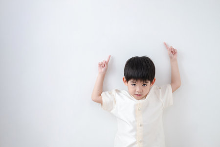 Asian boy Wearing traditional Thai clothing, standing with index finger upwards. on a white backgroundの写真素材