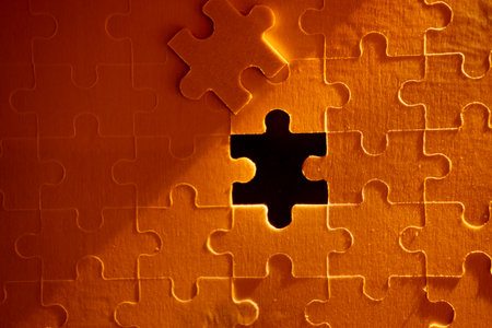 Pieces of a jigsaw puzzle filled with orange lights by hand Success conceptの写真素材