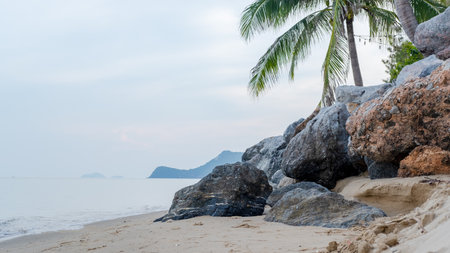 Beautiful beach Ocean waves blowing onto the beach and a large rock in front.の写真素材