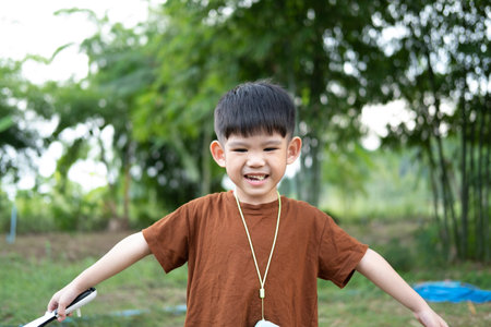 Asian boy standing with arms spread in a relaxed pose at outdoor areaの写真素材