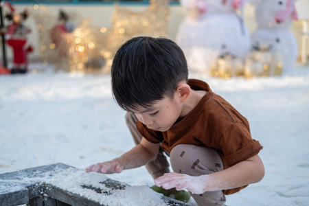 Little Asian boy playing in artificial snow during Christmas festivalの写真素材