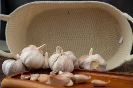 A large head of garlic lies on a wooden plate on a black background.の写真素材