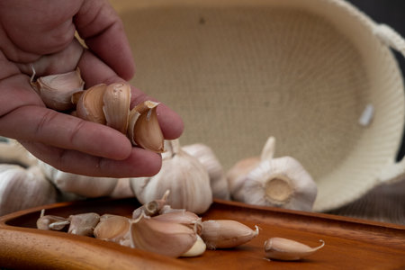 Male hands placing garlic on a wooden plateの写真素材