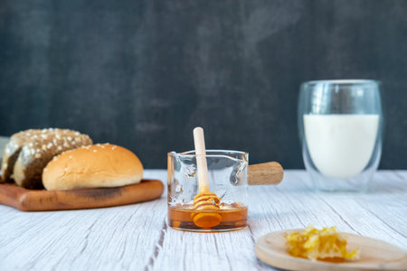 Breakfast set Honey in a measuring cup with bread and milkの写真素材