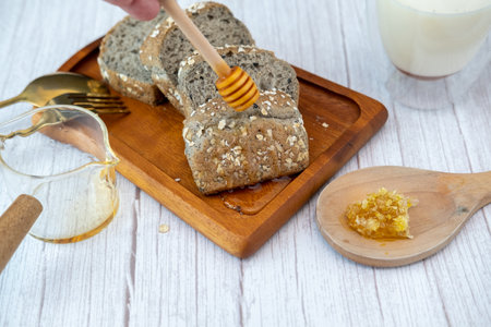Breakfast set A man's hand is pouring honey onto bread with milk.の写真素材