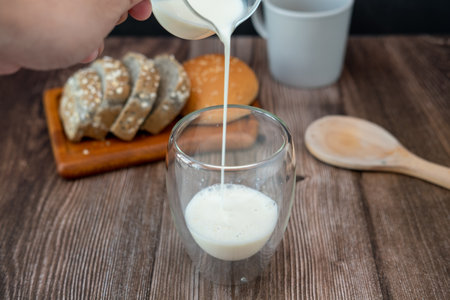 Breakfast set Male hands pouring milk onto glasses and slices of bread.の写真素材