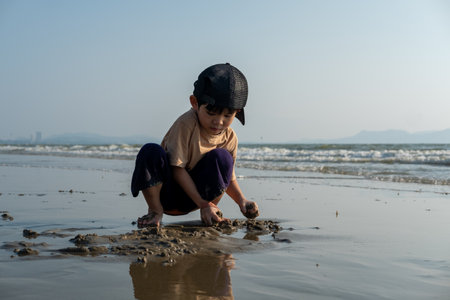 Little Asian boy playing in the sand at the sea beachの写真素材