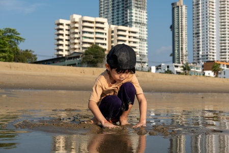 Little Asian boy playing in the sand at the sea beachの写真素材