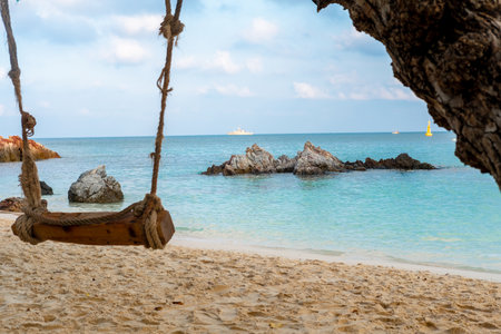 View of the beach, sea, beautiful rocks during the day and swings at the beach.の写真素材