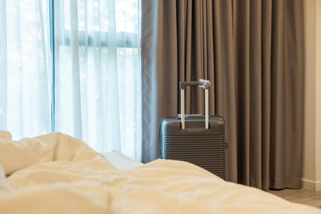 Large luggage positioned next to bedroom bed, highlighting relaxed travel lifestyle and planningの写真素材