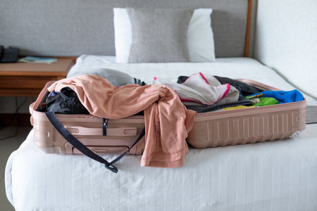 Traveler packing an open suitcase on the bed, organizing essentials for an upcoming journeyの写真素材