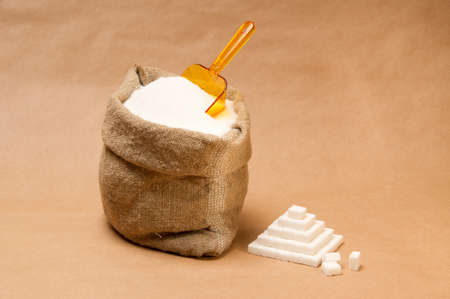 Sack with sugar and transparent plastic orange scoop on extra-strong paper backgroundの写真素材