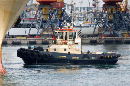 Towboat pushing a big ship at the harbor.