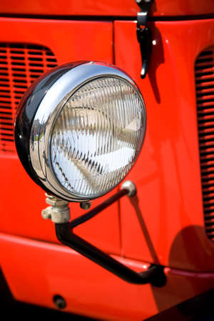 Antique headlight on red car.