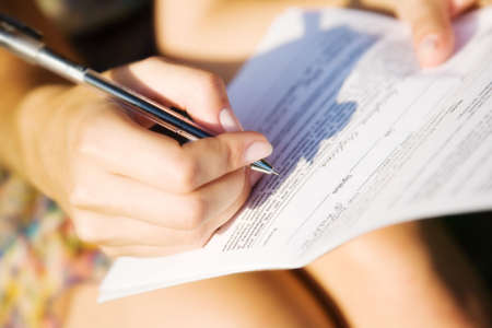 Young woman signing a document. Shallow dof.の写真素材