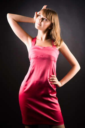 Young slim woman in pink dress. On dark background.の写真素材