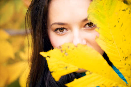 Woman with yellow leaves portrait. Focus on face.の写真素材
