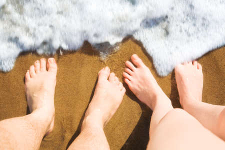 Man and woman legs on a beach in a surf.の写真素材