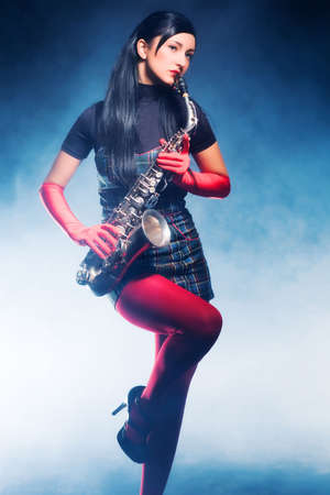 Young woman with saxophone. Smoky blue background.の写真素材