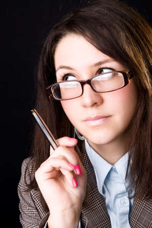 Young teacher holding pen. On dark background.の写真素材