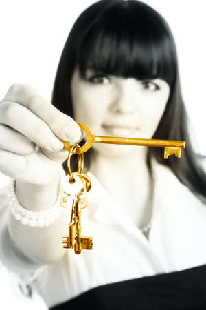 Businesswoman stretching gold keys. Isolated on white. Focus on keys.の写真素材
