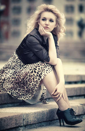 Pensive woman sitting on a stairs. Soft yellow tint.の写真素材