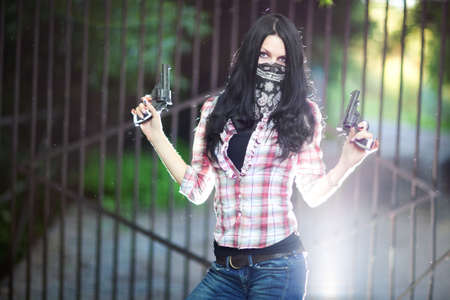 Young woman with guns. Shallow dof and light flash effect.の写真素材