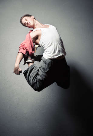 Young man jumping. On stone wall background.の写真素材
