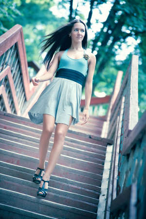 Young woman walking downstairs. Soft blue tint.