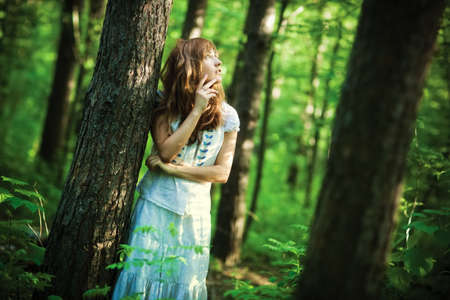 Young woman in forest. Dark saturated colors.の写真素材
