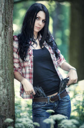 Young woman with guns in a forest.の写真素材