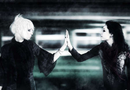 Two goth women touching hands on moving train background.