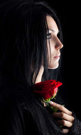 Brunette goth woman with rose portrait. Dark colors.の写真素材