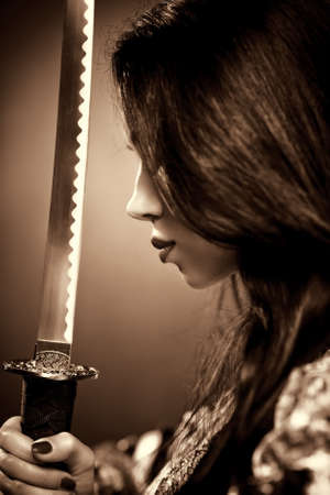 Young woman with samurai sword. Sepia color.の写真素材
