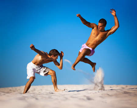 Two young men sport fighting on beach.の写真素材