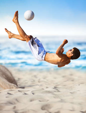 Young man playing soccer on beach.の写真素材