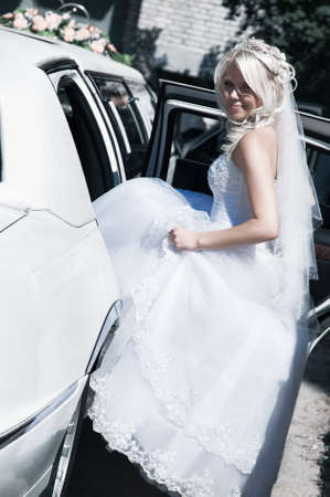 Young bride sitting to the car. Bright white colors.の写真素材
