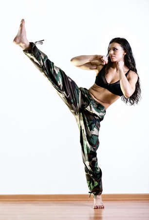 Young woman in military clothes kicking.の写真素材