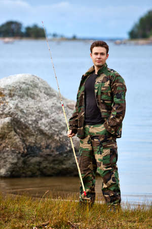 Young male fisher on lake shore.の写真素材