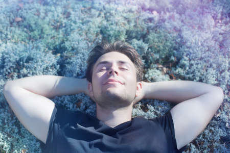 Young man resting on grass in forest.の写真素材