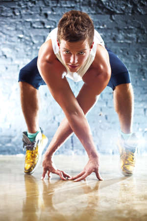 Young man sports exercises. On wall background.の写真素材