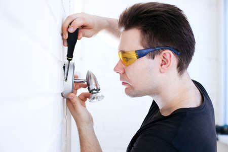 Man worker installing lamp on balcony 