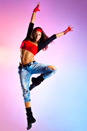 Young woman dancer jumping  On blue and pink background の写真素材