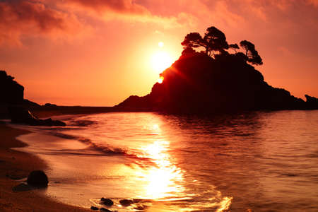 Coast with island at sunrise.の写真素材