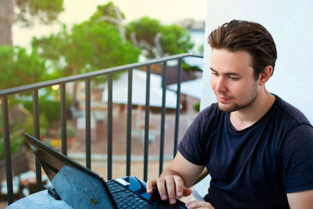 Young man working on laptop with outdoors view.の写真素材