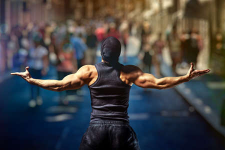 Young strong man standing on street against people.の写真素材