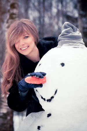 Young woman with snowman funny portrait の写真素材