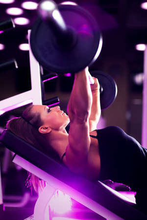 Young woman bodybuilder with barbell  Pink tint の写真素材